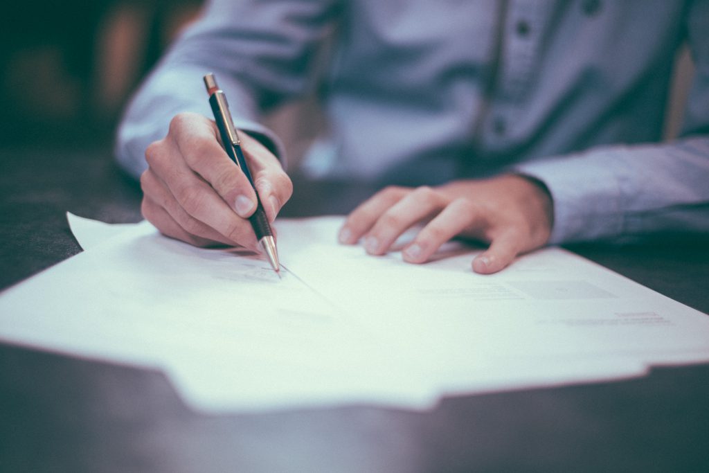 Man in smart shirt using a pen to make presentation notes on paper